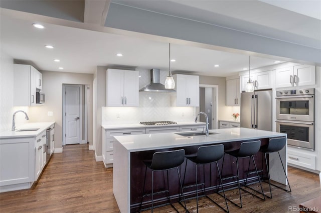 kitchen featuring sink, stainless steel appliances, white cabinets, and wall chimney exhaust hood