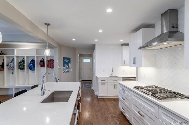 kitchen featuring stainless steel gas cooktop, sink, white cabinetry, tasteful backsplash, and wall chimney range hood