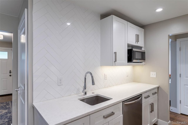 kitchen featuring dark wood-type flooring, sink, appliances with stainless steel finishes, white cabinets, and backsplash