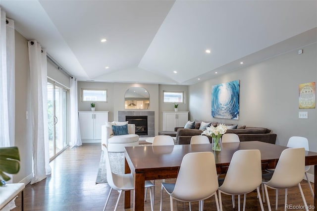 dining space with vaulted ceiling, a tile fireplace, and light hardwood / wood-style flooring