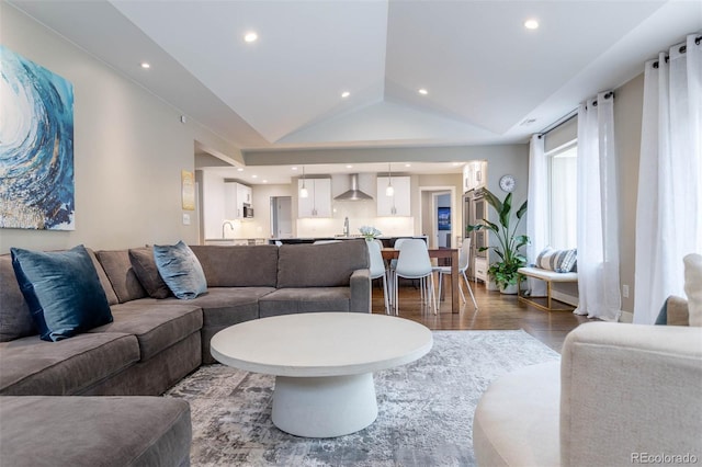 living room featuring sink, vaulted ceiling, and wood-type flooring