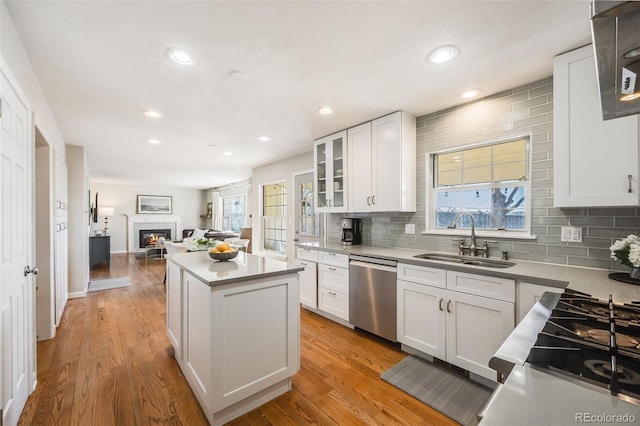 kitchen featuring stainless steel dishwasher, sink, a kitchen island, and white cabinets