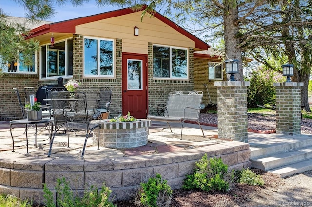 view of front facade featuring brick siding and a patio