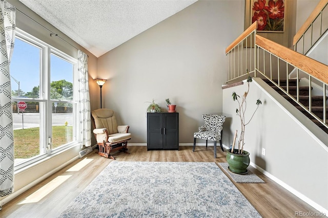 7830 Club Crest Dr, Arvada, CO 80005 - living area with wood finished floors, a textured ceiling, lofted ceiling, and stairway