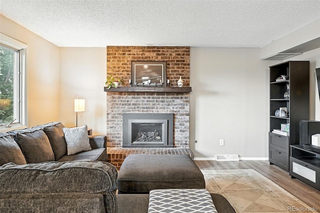 7830 Club Crest Dr, Arvada, CO 80005 - living room with wood finished floors, a textured ceiling, and a brick fireplace