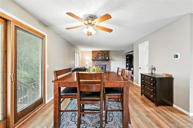 7830 Club Crest Dr, Arvada, CO 80005 - dining area with light wood-style flooring, ceiling fan, a textured ceiling, and a fireplace