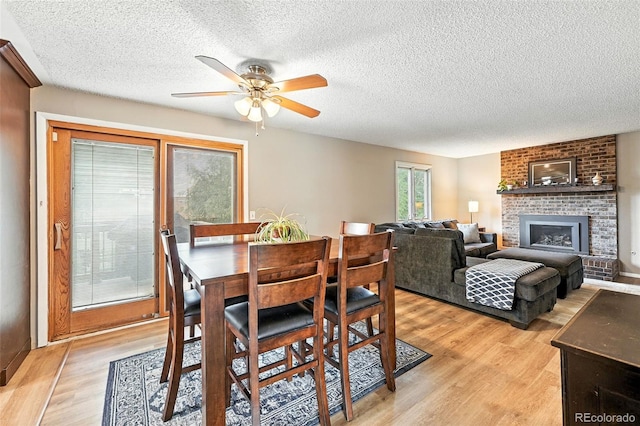 7830 Club Crest Dr, Arvada, CO 80005 - dining area featuring a ceiling fan, light wood-style flooring, a textured ceiling, and a brick fireplace