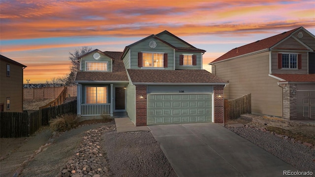 traditional-style house with a garage, driveway, brick siding, and fence