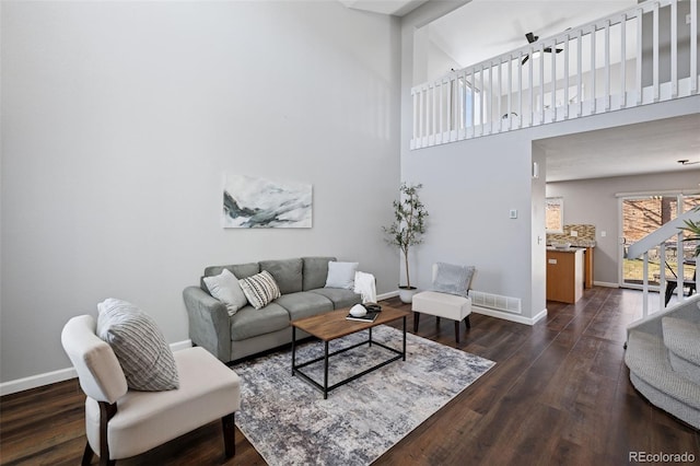 living room featuring dark wood-style floors, a high ceiling, visible vents, and baseboards