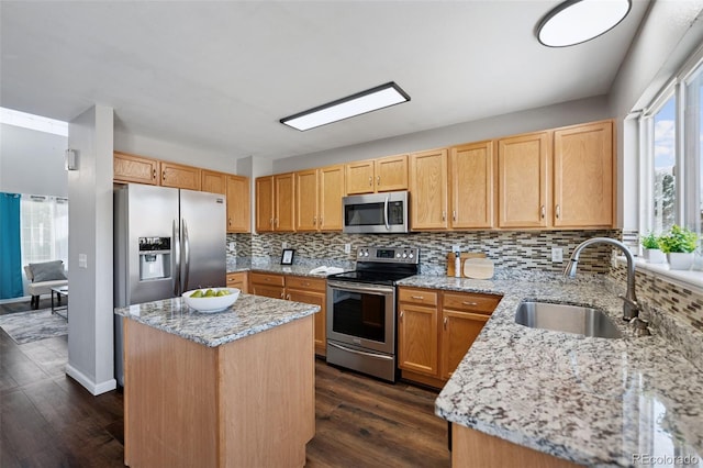 kitchen with stainless steel appliances, backsplash, dark wood-type flooring, a sink, and light stone countertops