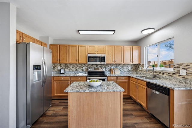 kitchen featuring dark wood-style flooring, appliances with stainless steel finishes, a kitchen island, and a sink