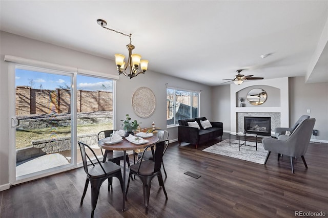 dining area featuring a glass covered fireplace, visible vents, dark wood finished floors, and baseboards