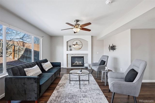 living area with baseboards, dark wood-type flooring, and a high end fireplace