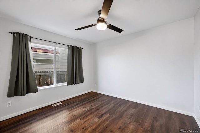 spare room with dark wood-style floors, baseboards, visible vents, and ceiling fan