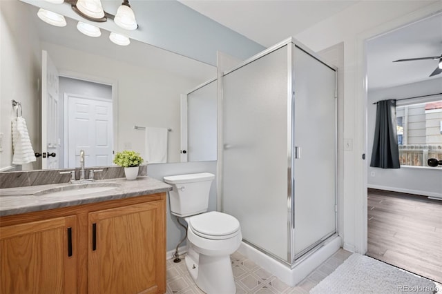 bathroom featuring toilet, a stall shower, vanity, and baseboards