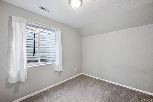 carpeted spare room with visible vents, vaulted ceiling, and baseboards