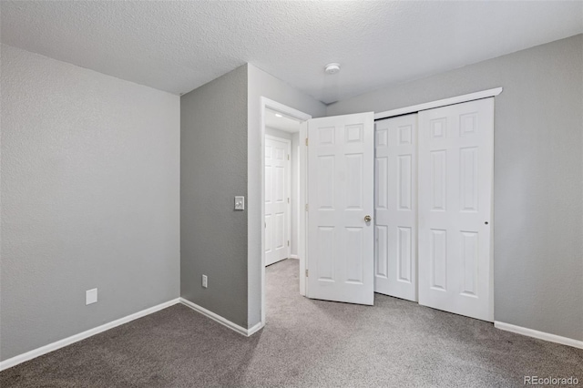 unfurnished bedroom featuring baseboards, a textured wall, carpet, a textured ceiling, and a closet