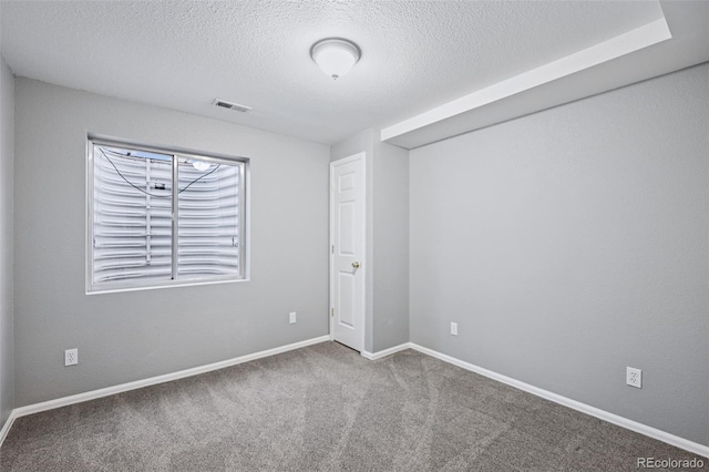 carpeted empty room featuring visible vents, a textured ceiling, and baseboards