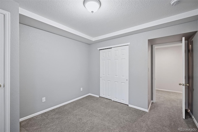 unfurnished bedroom with carpet floors, baseboards, and a textured ceiling