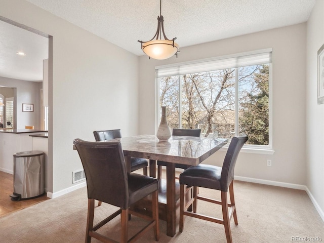 dining area with baseboards, plenty of natural light, light colored carpet, and visible vents