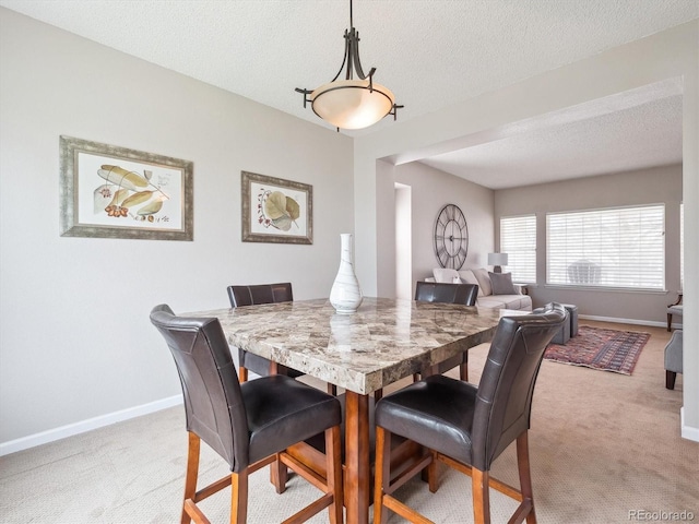dining space featuring baseboards, a textured ceiling, and light carpet