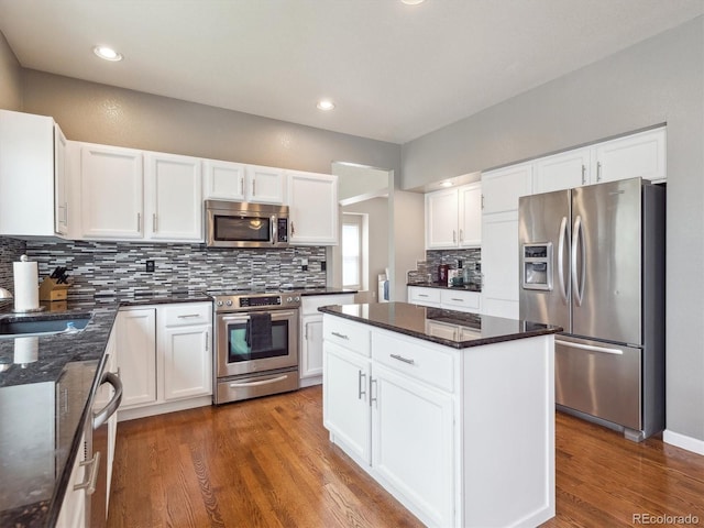 kitchen with dark wood-style flooring, a kitchen island, white cabinetry, tasteful backsplash, and appliances with stainless steel finishes