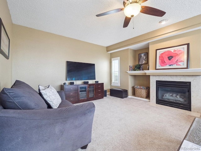 carpeted living area featuring a ceiling fan, a textured ceiling, and a tile fireplace