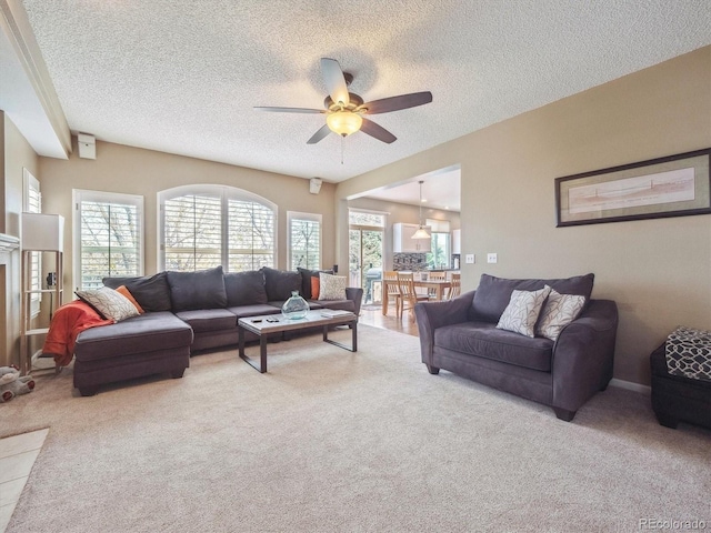 carpeted living area with a textured ceiling and ceiling fan