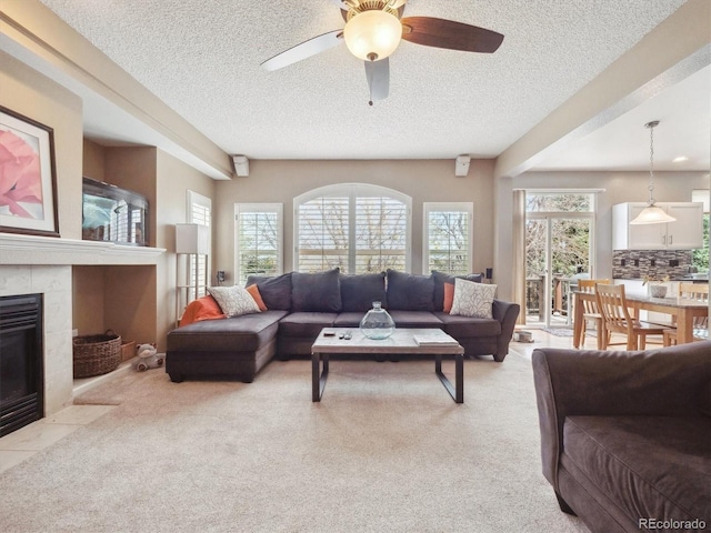 living area featuring carpet floors, a textured ceiling, and a tiled fireplace