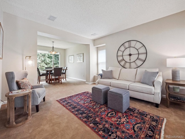 carpeted living room featuring baseboards, a textured ceiling, and visible vents