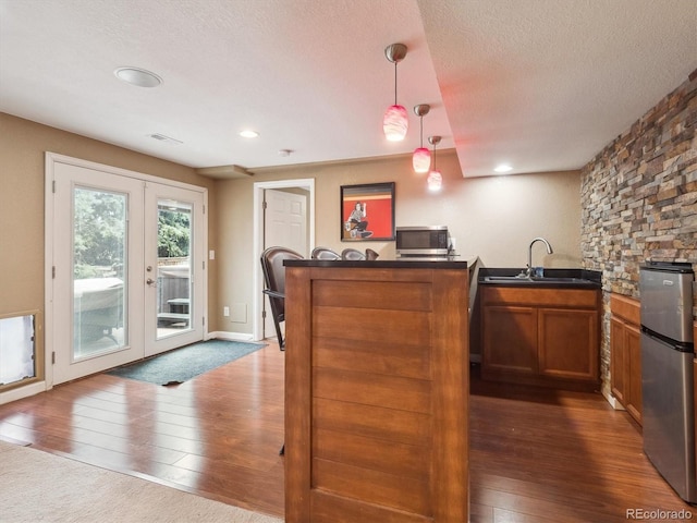 kitchen with a sink, a textured ceiling, french doors, stainless steel appliances, and a peninsula