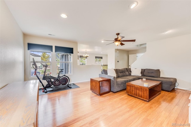 living room with ceiling fan with notable chandelier and light wood-type flooring