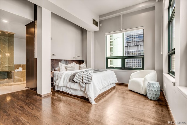 bedroom featuring ensuite bath and wood-type flooring