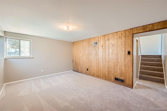 carpeted empty room featuring wood walls