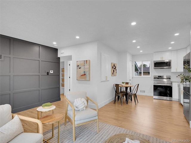 7126 Joan St, Denver, CO 80221 - living area with recessed lighting, light wood-style flooring, baseboards, and a decorative wall