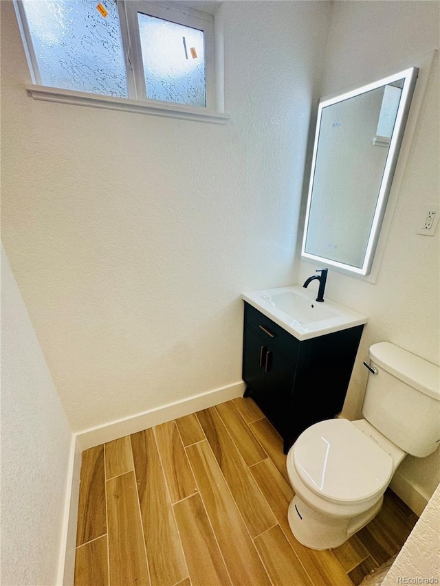 7126 Joan St, Denver, CO 80221 - bathroom featuring toilet, wood tiled floors, vanity, baseboards, and plenty of natural light