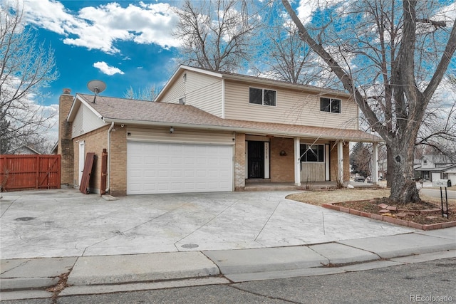 traditional-style home featuring an attached garage, fence, brick siding, and a chimney