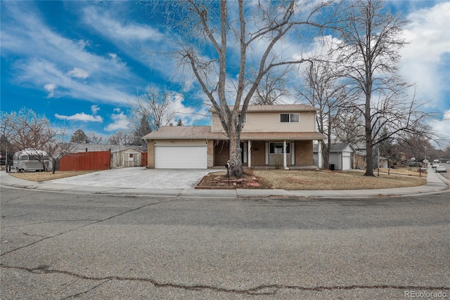 traditional-style home with a porch, fence, concrete driveway, a garage, and brick siding