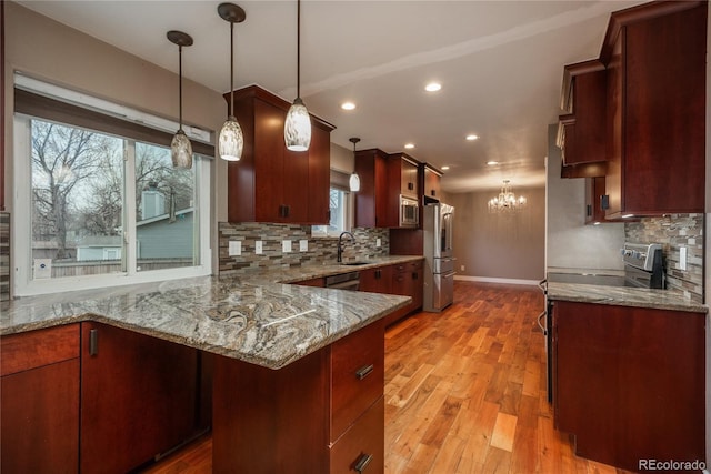 kitchen with backsplash, light wood-style flooring, appliances with stainless steel finishes, and light stone countertops