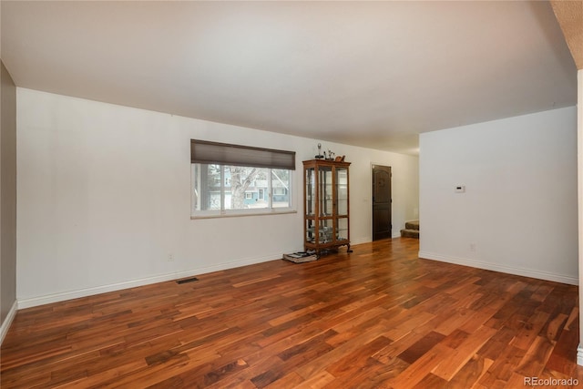 spare room with stairway, baseboards, visible vents, and wood finished floors