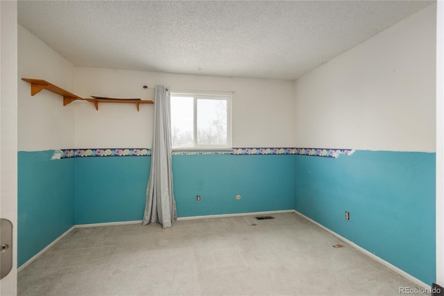 carpeted spare room featuring visible vents, baseboards, and a textured ceiling