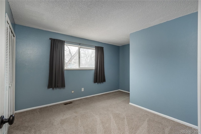 carpeted empty room featuring visible vents, baseboards, and a textured ceiling