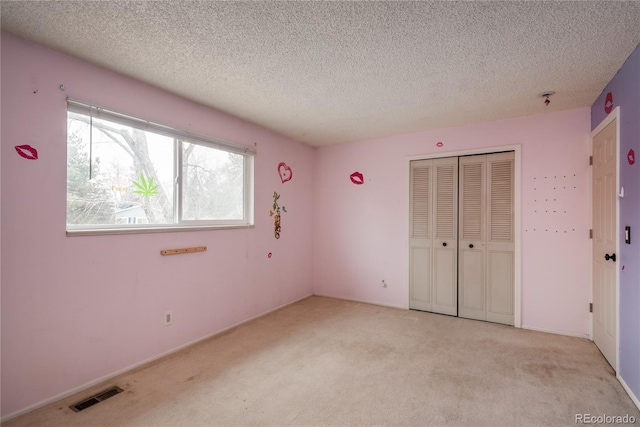 unfurnished bedroom with visible vents, a textured ceiling, a closet, and carpet flooring