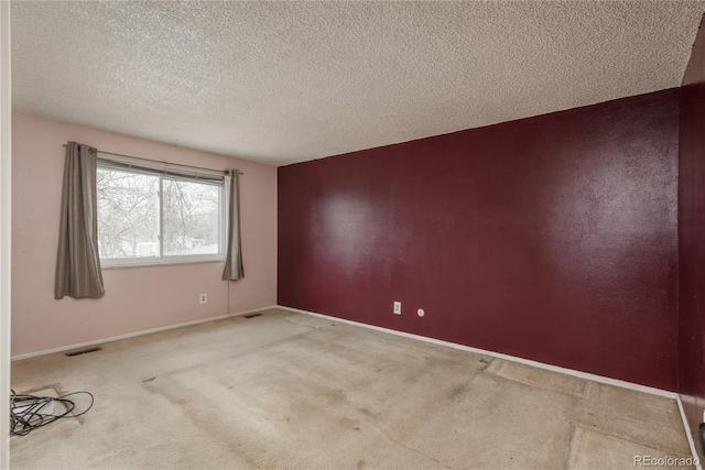 unfurnished room featuring baseboards, visible vents, carpet floors, and a textured ceiling