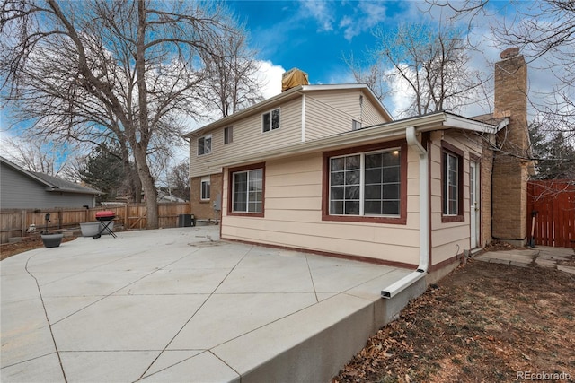 rear view of house featuring central air condition unit, a patio area, a fenced backyard, and a chimney