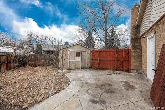 view of yard with a gate, a fenced backyard, a storage shed, an outdoor structure, and a patio area