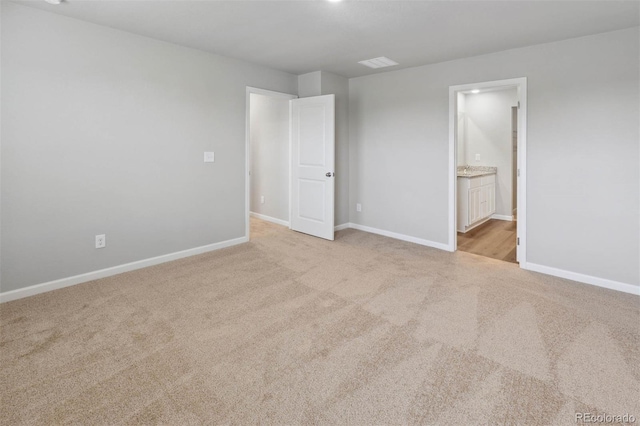 unfurnished bedroom featuring connected bathroom, baseboards, and carpet flooring