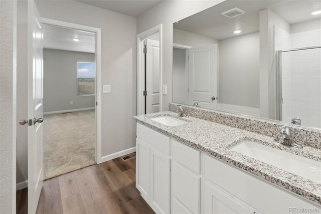 full bathroom featuring double vanity, visible vents, a sink, and wood finished floors