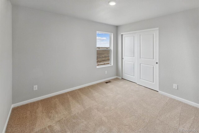 unfurnished bedroom with light carpet, baseboards, visible vents, and a closet