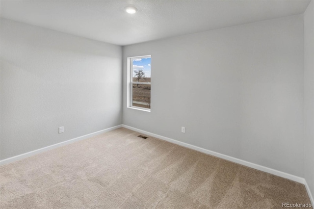 spare room with carpet floors, baseboards, and visible vents